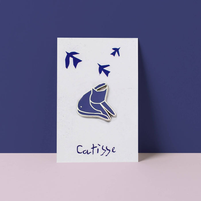 Blue cat enamel pin on a white card with 'Catisse' branding against a purple background