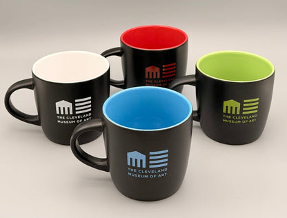 Four black mugs with colored interior and exterior, featuring The Cleveland Museum of Art logo.