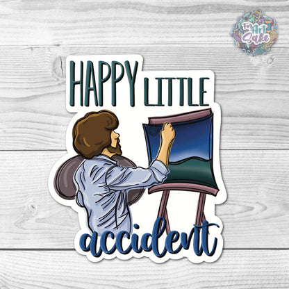 Sticker with illustration of a person holding a painting and text 'Happy Little Accident' on a wooden surface.
