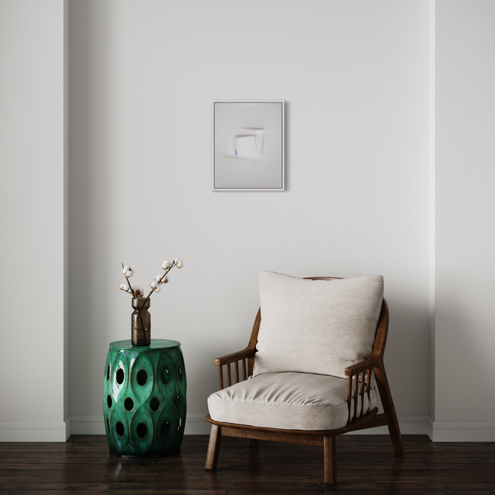 The artwork 'Two Equal Lovers 10' by Debra Ramsay features minimalist geometric shapes in ink on polyester resin film, displayed in a modern interior setting above a mid-century wooden armchair with beige cushions and alongside an emerald green ceramic garden stool with decorative cutouts, accented by white cotton stems in a vase. By Debra Ramsay.